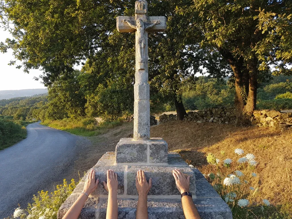 Recreación: o cruceiro de pedra de novo no seu sitio, á beira dunha estrada, con tres pares de mans na base